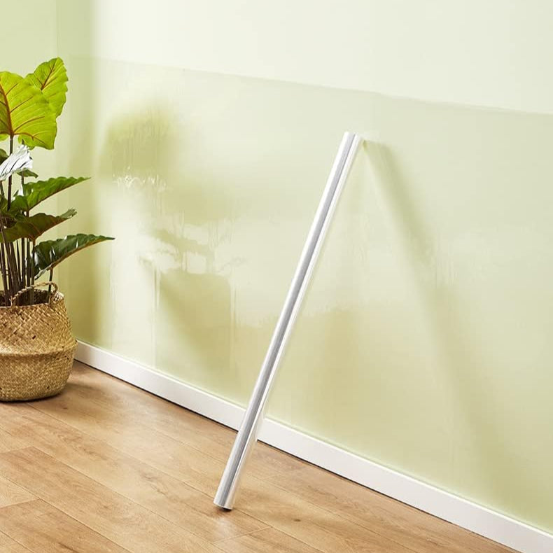 White cylindrical object leaning against a light green wall with a plant on the left.