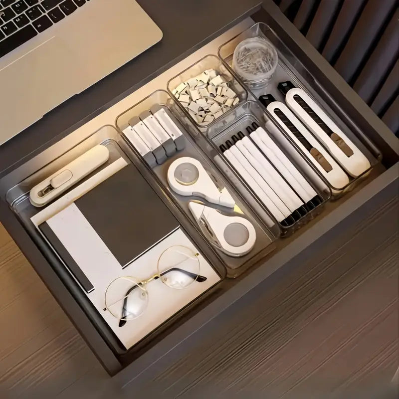 Organized desk drawer with stationery items including pens, scissors, and glasses.