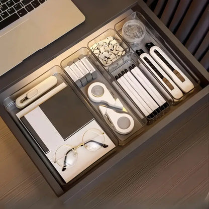 Organized desk drawer with stationery items including pens, scissors, and glasses.